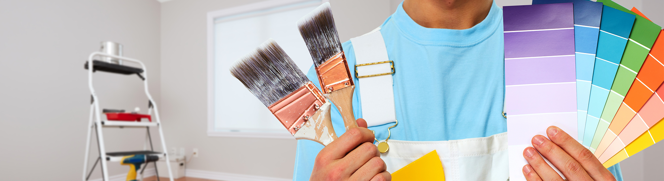 Painter holding brushes on one hand and color samples on the other